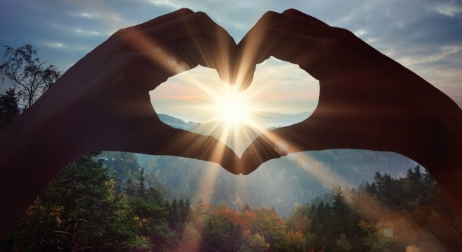 Composite image of hands making heart shape on the beach