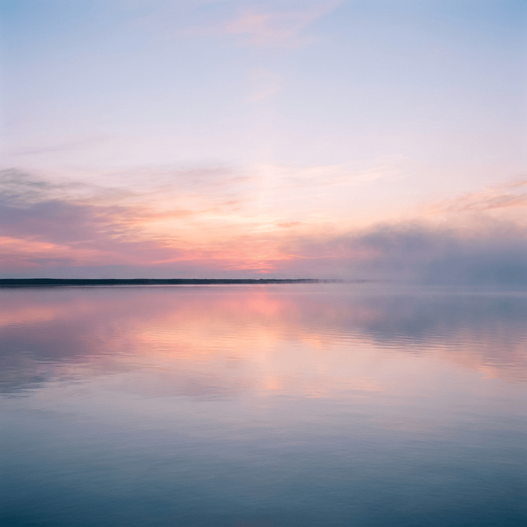 Pastel sunset sky reflecting across calm, misty water